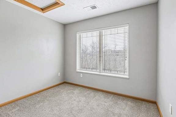 Carpeted bedroom with window and ceiling light.