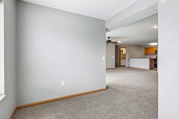 Open living area with carpeted floors and view into kitchen.
