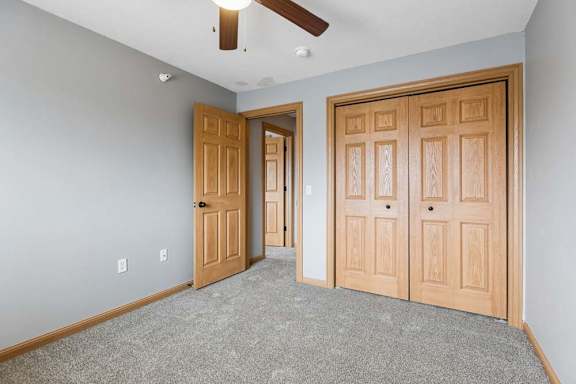 Bright apartment bedroom with neutral carpet, gray walls, wood-trimmed doors, and double bi-fold closet doors offering ample storage.