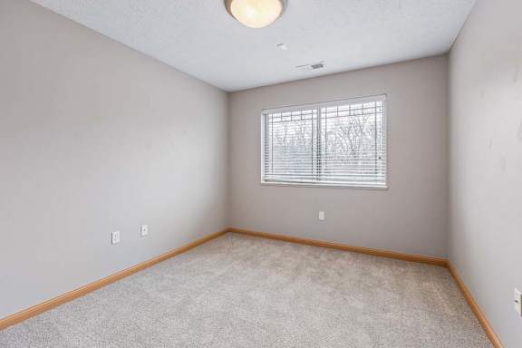 Carpeted bedroom with window and ceiling light.