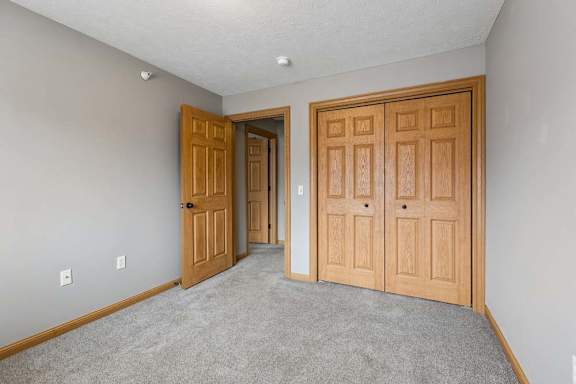 Carpeted bedroom with double closet doors and interior doorway.