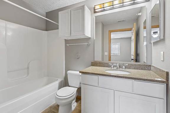 Bathroom with white vanity, granite countertop, and tub-shower combination.