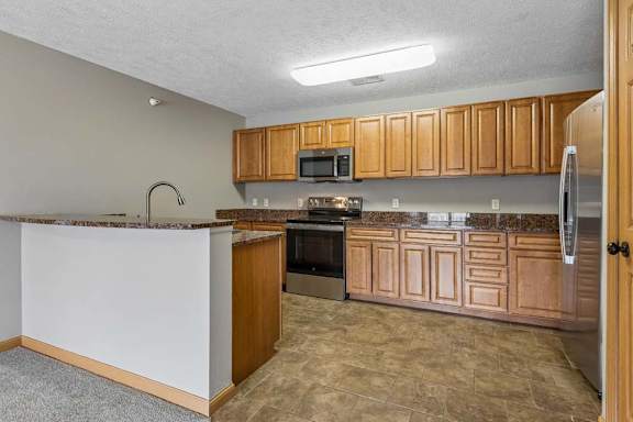 Open-concept kitchen with breakfast bar, granite countertops, and wood-style cabinetry.