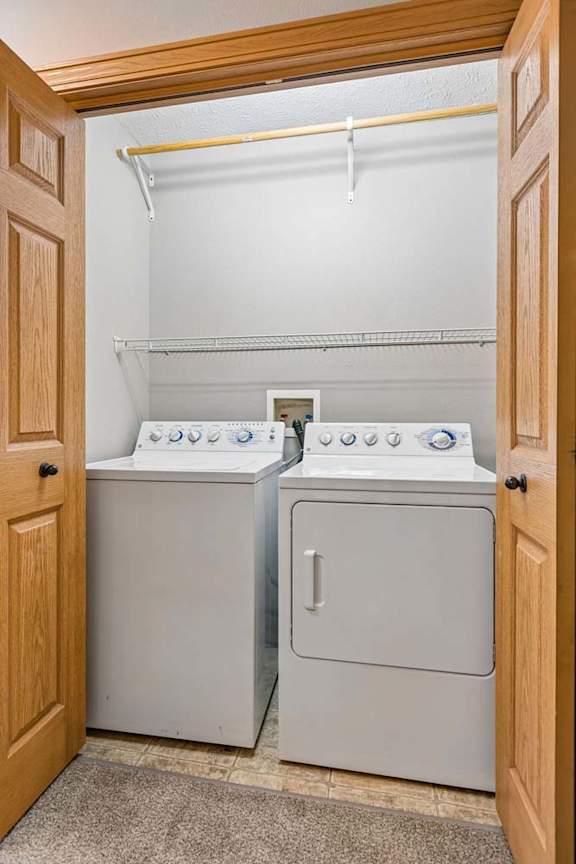 Apartment laundry closet with a washer and dryer, wire shelving for storage, and bi-fold doors for convenient access.