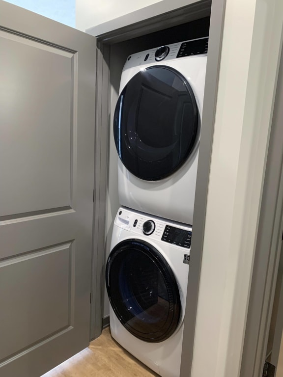 Stacked front loader washer and dryer in a closet with door.