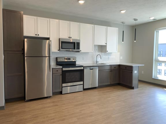 Kitchen with brown lower cabinets, white upper cabinets and bar seating at Haven at Uptown.