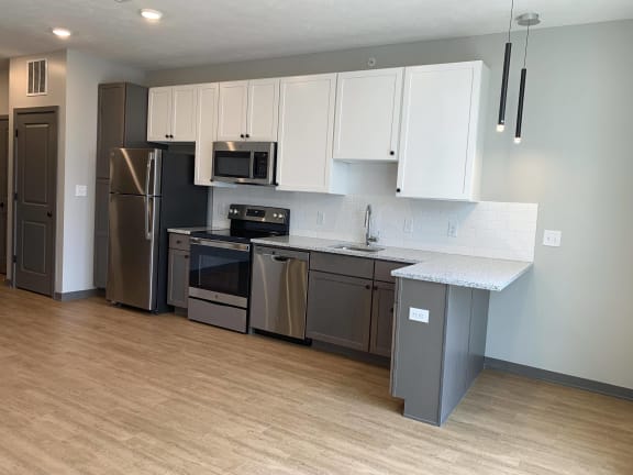 Kitchen with brown lower cabinets, white upper cabinets and bar seating at Haven at Uptown