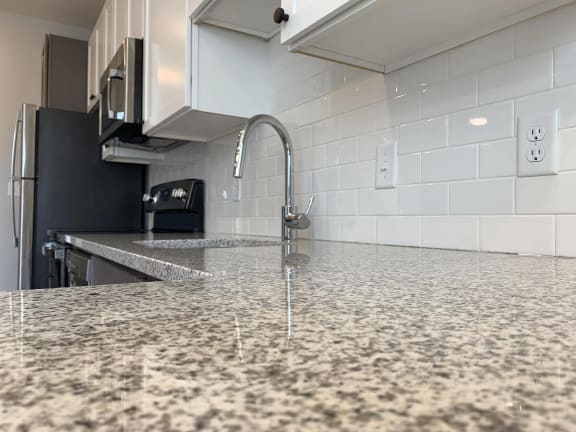 Close up of light granite counters and white subway tile backsplash