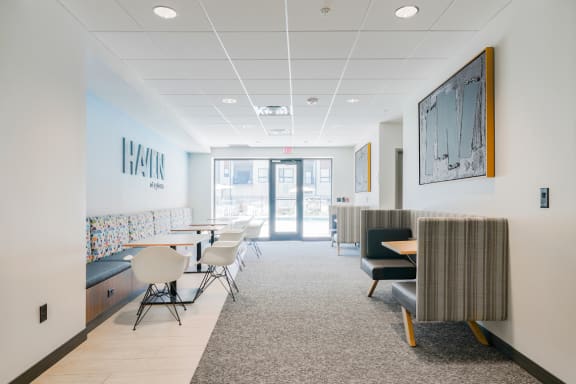 a large room with tables and chairs and a hallway with glass doors