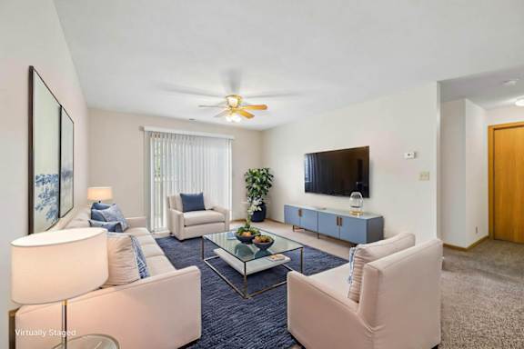 Virtually staged living room with two armchairs, a wall-mounted TV, coffee table, sliding glass door, and neutral finishes.