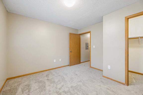 Bedroom with soft carpeting, an open closet with a hanging rod, and direct access to the hallway.