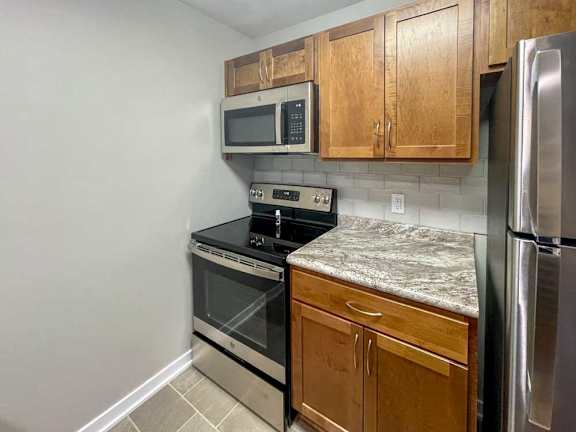 a kitchen with updated wooden cabinets, granite countertops, and stainless steel appliances