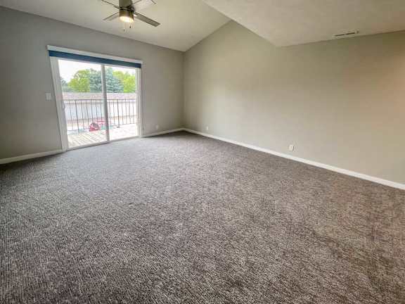 a living room with a ceiling fan and carpeted floor