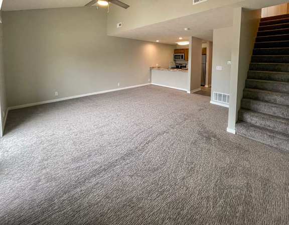 a spacious living room with a staircase leading to the second floor bedroom