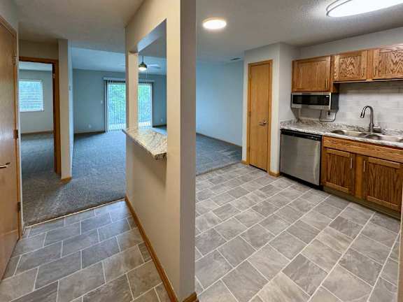 A kitchen with wooden cabinets, and a windowed divider wall with built in countertop.