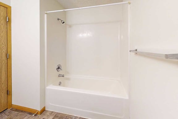 A white combo shower and tub with a metal towel rack on the right