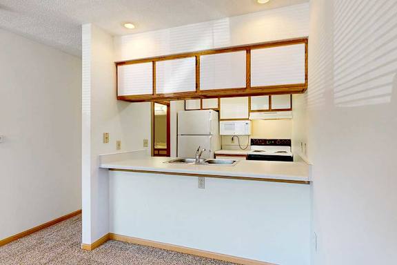 A kitchen with passthrough counter and overhead lighting