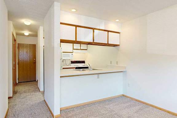 A galley kitchen layout with white range, a passthrough window, and wood trim cabinetry