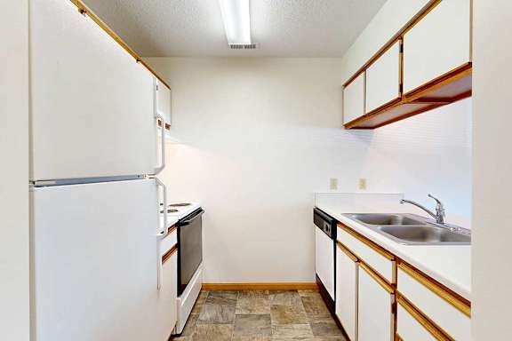 A kitchen with white appliances, white and wooden cabinetry, and dual sink