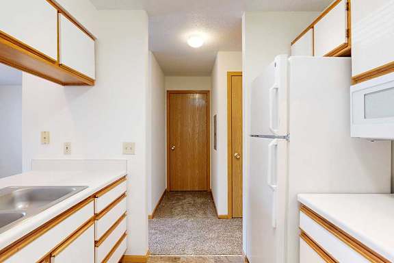 A galley kitchen with white appliances and wooden cabinets