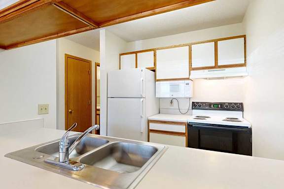 Kitchen with white appliances, white and wooden cabinetry, and a double basin sink