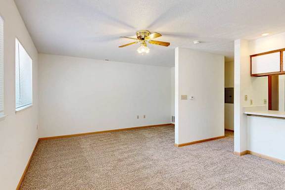 Alternate view of living room with light walls and ceiling fan