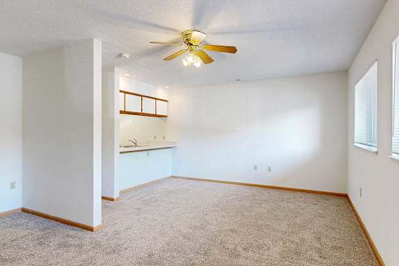 Open living space with carpet flooring and ceiling fan