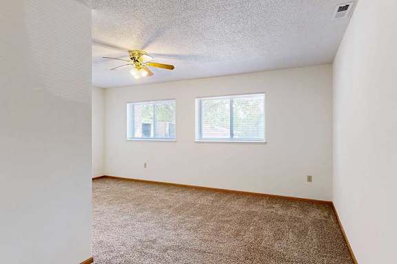 Carpeted sleeping area with ceiling fan and two windows