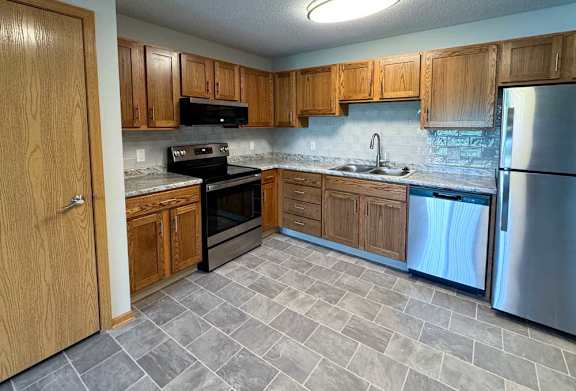 a kitchen with wooden cabinets and stainless steel appliances