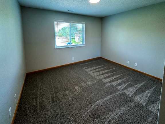 a bedroom with a window and a carpeted floor