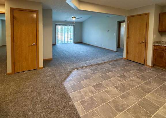 a spacious living room next to an open kitchen with tiled flooring