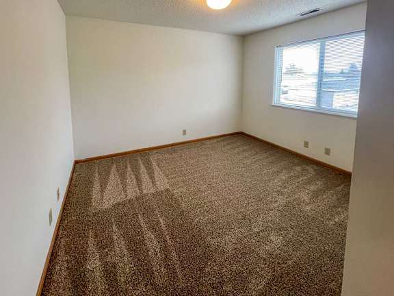 A bedroom with a carpeted floor and a large window.