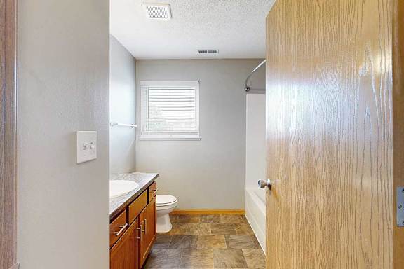 A bathroom with a toilet, sink, and window.