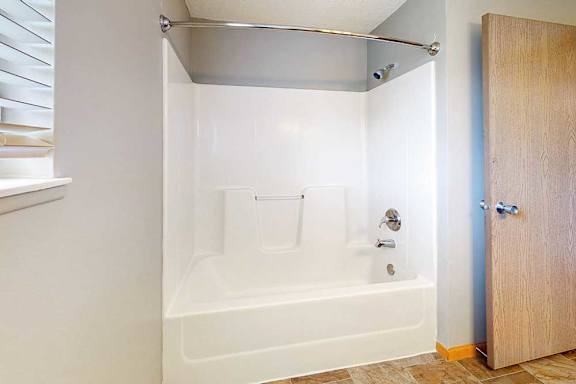 a bathroom with a combo bathtub-shower and vinyl flooring