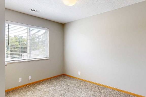 a den space with carpeted flooring and a wide window