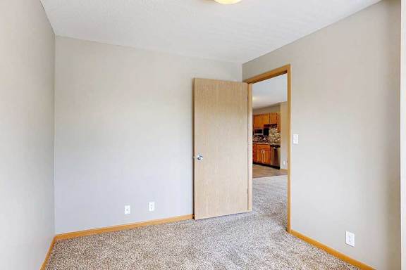 a den space with grey carpet and a door to the living room