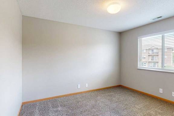 a bedroom with carpet, overhead lighting, and a large window