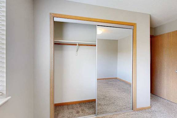 an open bedroom closet with sliding mirrored doors