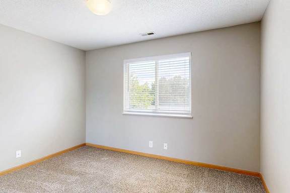 a bright bedroom with carpet, overhead light, and large window
