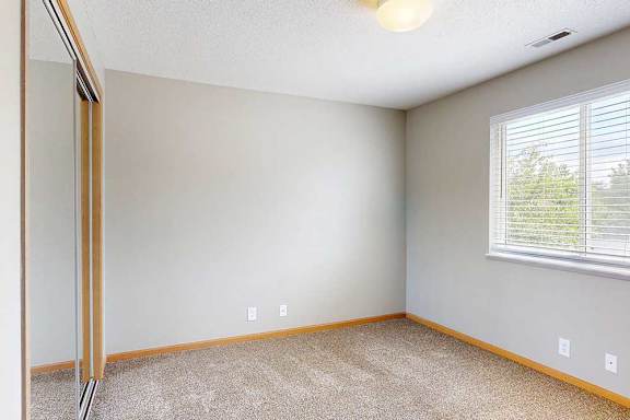 a bedroom with carpet, large window, and closet with sliding mirror doors