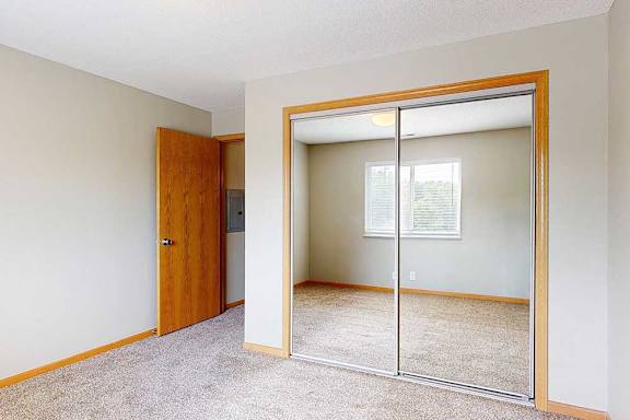 a bedroom with carpet and a closet with mirrored sliding doors