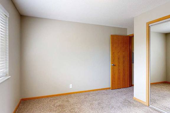 a bedroom with carpet, large window, and closet with sliding mirror doors