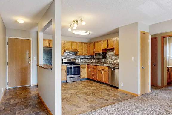 a kitchen with stainless steel appliances, wood cabinetry, and tile backsplash