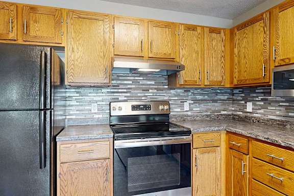 a kitchen with stainless steel appliances, wood cabinetry, and tile backsplash