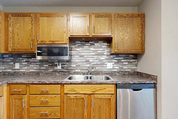 a kitchen with stainless steel appliances, double basin sink, and wooden cabinets