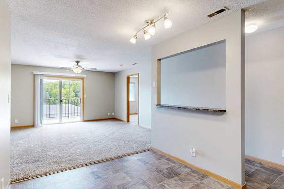 a kitchen with vinyl flooring and overhead light adjacent to an open living room