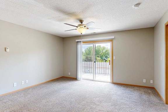 a bright carpeted living room with large sliding glass door