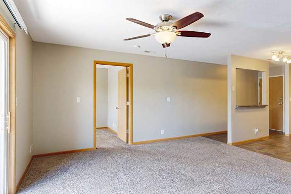 a living room with ceiling fan, sliding glass door, and door to the den space