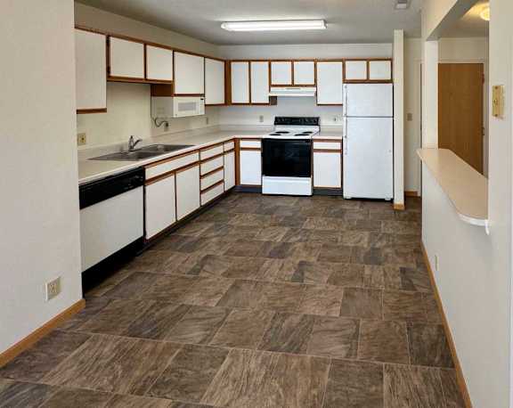a kitchen with white appliances and white cabinets with oak trim