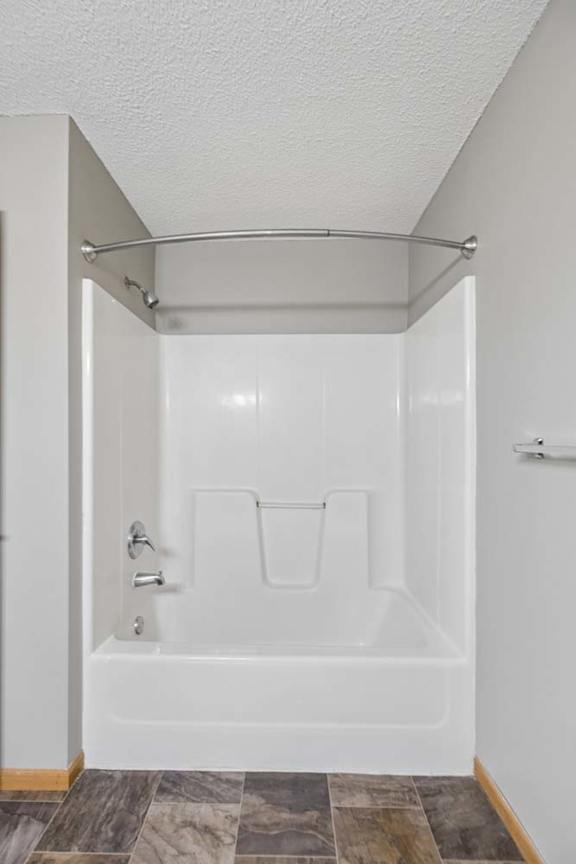 A white bathroom with a walk-in shower and a tile floor.